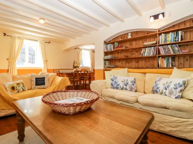 A living room with sofas cushions a wooden coffee table bookshelf and a dining table with chairs at The Pound in Trellech near Monmouth