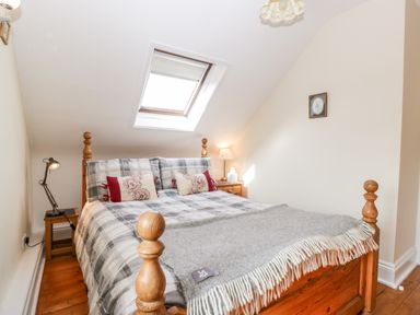 A bedroom with a wooden bed under a skylight window and bedside tables with lamps at The Pound in Trellech near Monmouth