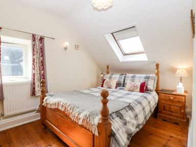 A bedroom with a wooden bed and nightstand under a skylight window at The Pound in Trellech near Monmouth