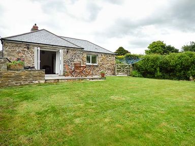 A stone house with a patio table and chairs and a lawn at Shepherds Rest in Jacobstow near Bude