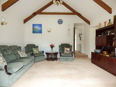 A living room with green sofas wooden beams and a wooden cabinet at Shepherds Rest in Jacobstow near Bude