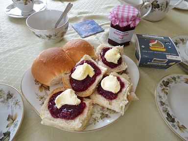 A plate with bread rolls spread with raspberry jam and butter on a table with cups and a jar of jam at Shepherds Rest in Jacobstow near Bude