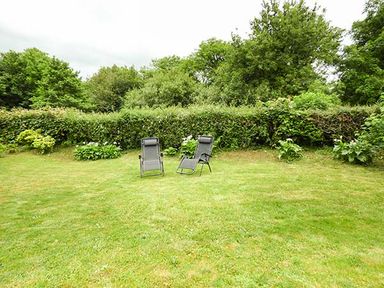 Two reclining chairs on a lawn surrounded by shrubs and trees at Shepherds Rest in Jacobstow near Bude