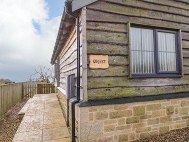 Exterior corner of a wooden building with stone base and a window with frosted glass and blinds at Coquet in Longframlington near Alnwick