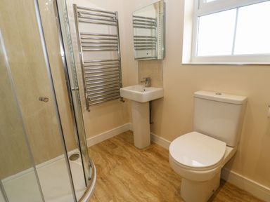 A bathroom with a shower enclosure a toilet a pedestal sink a heated towel rail and a window at Coquet in Longframlington near Alnwick