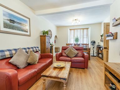 A living room with two red leather sofas a wooden coffee table and a dining table by the window at Dringarth in Tenby