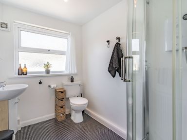 A bathroom with a toilet sink shower and storage baskets at Dringarth in Tenby