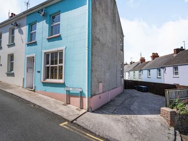 Exterior of pastel colored terraced houses along a street with a sign reading Park Terrace at Dringarth in Tenby