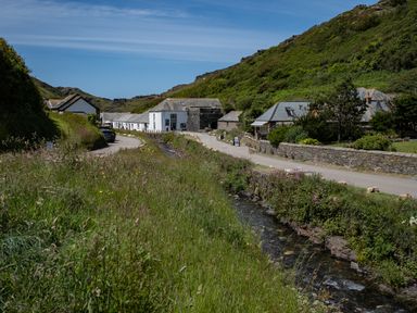 A small village road with white houses along a stream and green hills in the background at Cobble Cottage Boscastle near Tintagel