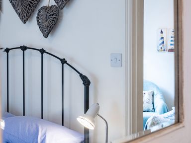 A bedroom with a black metal bed frame a bedside lamp and wicker heart decorations on the wall at Cobble Cottage Boscastle near Tintagel