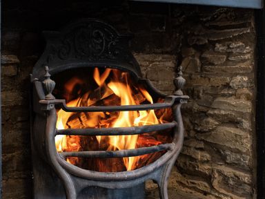 A close-up of a burning fire in a cast iron fireplace with a stone wall background at Cobble Cottage in Boscastle near Tintagel
