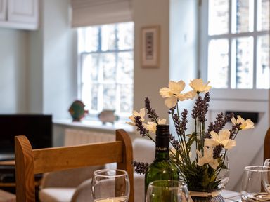 A dining table with a bottle of wine glasses and a flower arrangement in a room at Cobble Cottage Boscastle near Tintagel