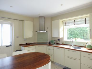 A kitchen with cream cabinets wooden countertops a stainless steel range hood a toaster kettle and a window with a blind at Woodbine Cottage in Old Leighlin near Kilkenny County Kilkenny