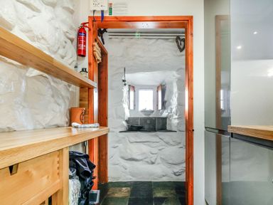 A narrow room with white stone walls wooden countertops and a fire extinguisher at Hwylfa'r Groes Talybont near Barmouth