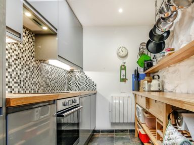 A kitchen with wooden countertops gray cabinets a tiled backsplash and hanging pots at Hwylfa'r Groes in Talybont near Barmouth