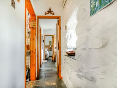 A hallway with stone walls and wooden door frames leading to a bedroom at Hwylfa'r Groes in Talybont near Barmouth