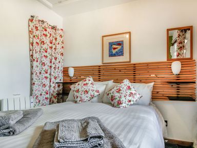 A bedroom with a double bed with floral cushions and matching curtains at Hwylfa'r Groes Talybont near Barmouth
