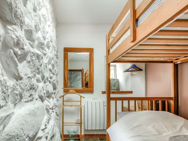 A bedroom with bunk beds a wooden mirror and a white stone wall at Hwylfa'r Groes Talybont near Barmouth