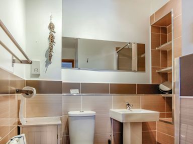 A bathroom with a toilet sink mirror and shelves at Hwylfa'r Groes in Talybont near Barmouth