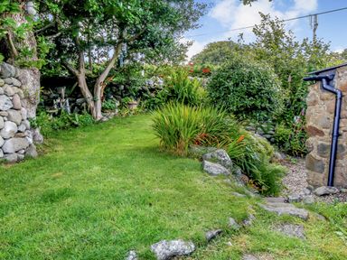A garden with grass stone walls and various plants at Hwylfa'r Groes Talybont near Barmouth