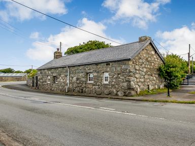 A stone cottage with small windows beside a road at Hwylfa'r Groes in Talybont near Barmouth