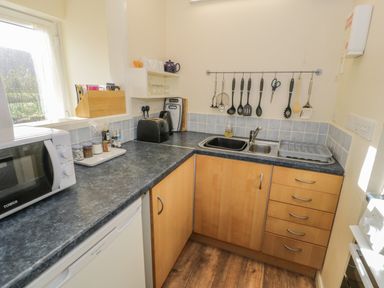 A kitchen with a microwave toaster and utensils hanging above the sink at Bryn Melyn Artists Cottage Llanelltyd near Dolgellau