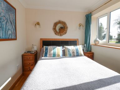 A bedroom with a double bed between two wooden bedside tables under a round mirror at The Lodge in Coltishall
