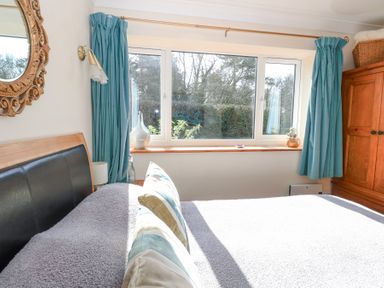 A bedroom with a bed a wooden wardrobe blue curtains and a window at The Lodge in Coltishall