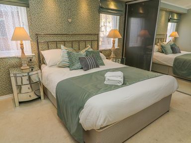 A bedroom with a bed pillows lamps mirrored bedside tables and a wardrobe at Shore Beats Work - Capenwray 10 in South Lakeland Leisure Village