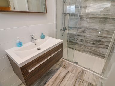 A bathroom with a sink vanity and a glass-enclosed shower at Shore Beats Work - Capenwray 10 in South Lakeland Leisure Village
