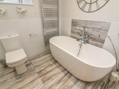 A bathroom with a freestanding bathtub toilet and heated towel rail at Shore Beats Work - Capenwray 10 South Lakeland Leisure Village