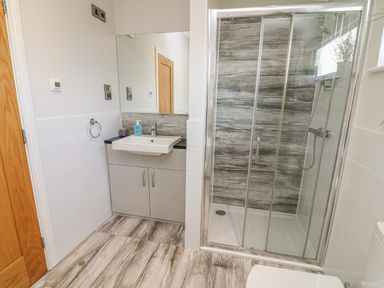A bathroom with a sink and cabinet a glass shower enclosure and tiled floor at Shore Beats Work - Capenwray 10 South Lakeland Leisure Village