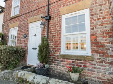An outdoor view of a brick exterior with a door and windows at Croft View in Fylingthorpe near Robin Hood's Bay
