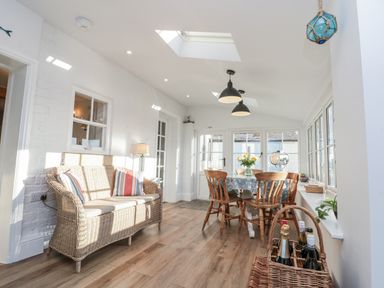 A conservatory with a dining table and wicker sofa at Croft View Fylingthorpe near Robin Hood's Bay
