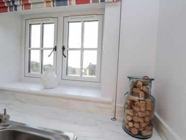 A kitchen with a sink, pitcher, cork jar, and windows at Croft View in Fylingthorpe near Robin Hood's Bay