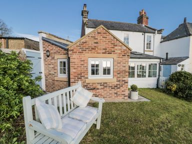 A garden with a bench and a brick cottage at Croft View in Fylingthorpe near Robin Hood's Bay
