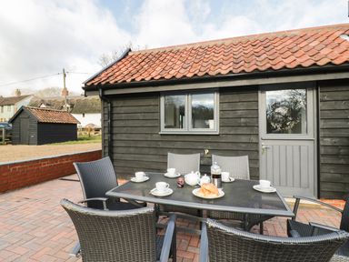 An outdoor patio with a table set for coffee with cups croissants and a coffee press at Whitehands Farm Barn in Old Buckenham