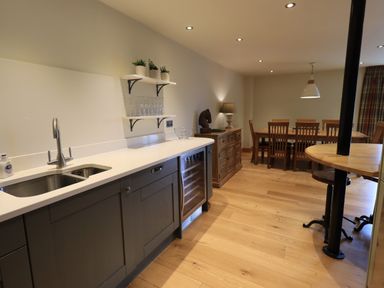 A kitchen area with a countertop sink wooden dining table and chairs at Yew Cottage in Backbarrow