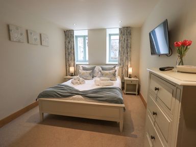 A bedroom with a double bed and bedside tables with lamps at Yew Cottage in Backbarrow