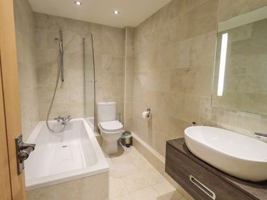 A bathroom with a bathtub shower toilet sink and mirror at Yew Cottage in Backbarrow