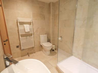 A bathroom with a toilet sink shower and towel radiator at Yew Cottage in Backbarrow