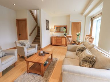 A living room with armchairs sofa coffee table and dining table at Lime Cottage in Backbarrow near Newby Bridge