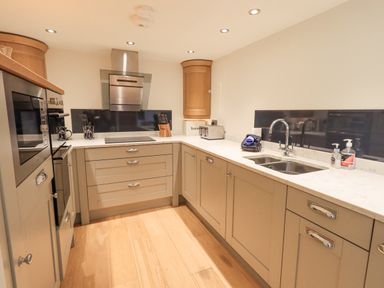 A kitchen with wooden cabinets a double sink a toaster and built in oven at Lime Cottage in Backbarrow near Newby Bridge