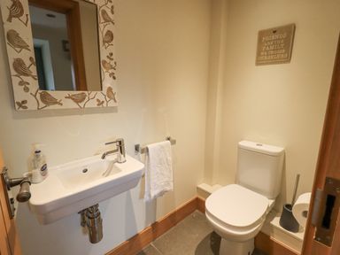 A small bathroom with a wall-mounted sink mirror and toilet at Lime Cottage in Backbarrow near Newby Bridge