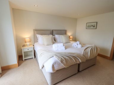 A bedroom with a double bed bedside tables lamps and folded towels at Lime Cottage in Backbarrow near Newby Bridge