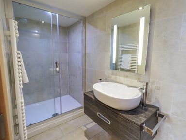 A bathroom with a glass-enclosed shower and a sink with a mirror above at Lime Cottage Backbarrow near Newby Bridge