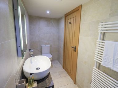 A bathroom with a sink toilet wooden door and towel rail at Lime Cottage Backbarrow near Newby Bridge