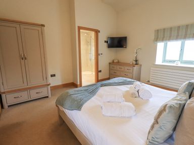 A bedroom with a bed, wardrobe, chest of drawers, and a window at Lime Cottage in Backbarrow near Newby Bridge