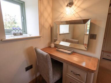 A vanity desk with a mirror chair and light next to a window at Lime Cottage in Backbarrow near Newby Bridge