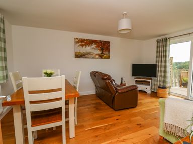 A living room with dining table chairs leather sofa and television at Foxes Meadow in Howey near Llandrindod Wells